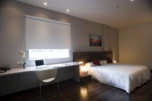 a bedroom with a bed and a desk with a laptop at Hotel Beasain in Beasain