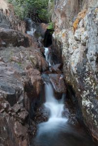 una corriente de agua fluyendo a través de rocas en un cañón en Bateleur Nature Reserve, en Modimolle