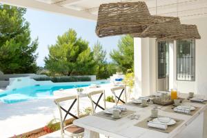 a dining table and chairs on a patio with a pool at Anemolia Villas with private pools near the most beautiful beaches of Alonissos in Alonnisos