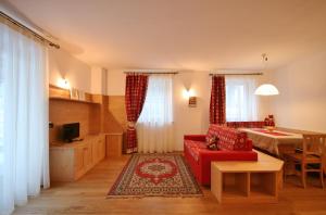 ein Wohnzimmer mit einem roten Sofa und einem Tisch in der Unterkunft Casa Pecol in Falcade