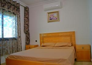 1 dormitorio con 1 cama con cabecero de madera y ventana en Résidence Rive D'or, en Martil