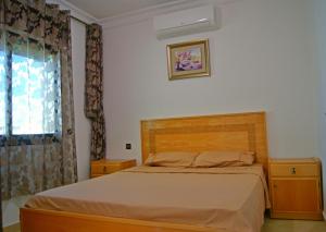 a bedroom with a bed with a wooden headboard and a window at Résidence Rive D'or in Martil