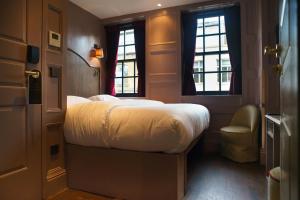 a bedroom with a large bed and two windows at Mimi's Hotel Soho in London