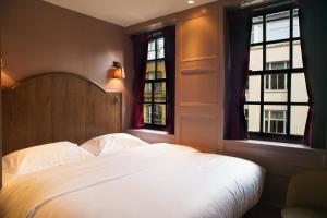 a bedroom with a white bed and two windows at Mimi's Hotel Soho in London
