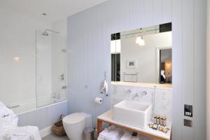 W łazience znajduje się umywalka, toaleta i lustro. w obiekcie The Crown Hotel w mieście Woodbridge