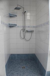 a shower in a bathroom with white tiles at Landhaus-Altebrücke in Wangerland