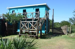 una casa azul con una escalera de madera que conduce a ella en La Brújula Hostel, en La Paloma