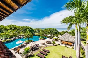 an aerial view of a resort with a pool and palm trees at Hacienda Pinilla Vacation Rentals in Tamarindo