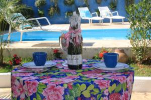 uma mesa com duas chávenas azuis e uma garrafa de vinho em Canto das Laranjeiras Villa no Guarujá