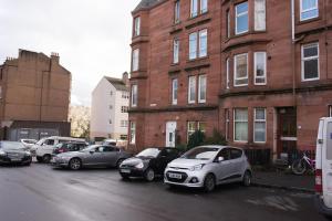 eine Reihe von Autos, die auf einem Parkplatz vor den Gebäuden geparkt sind in der Unterkunft PREMIER - Crathie View Apartment in Glasgow