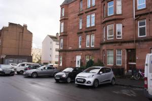 a row of cars parked in a parking lot in front of buildings at PREMIER - Crathie View Apartment in Glasgow