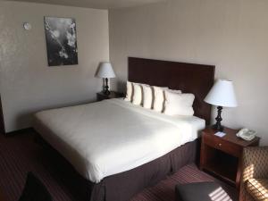 a hotel room with a large bed with white sheets and pillows at Territorial Inn Guthrie Oklahoma in Guthrie