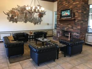 een wachtkamer met lederen meubels en een televisie bij Territorial Inn Guthrie Oklahoma in Guthrie