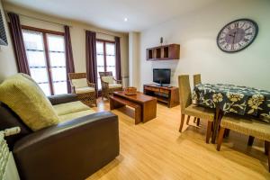 a living room with a table and chairs and a clock at Apartamentos El Cordial De Fausto in Llanes