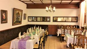 a dining room with white tables and chairs and a chandelier at Hotel Rath in Schwalmtal