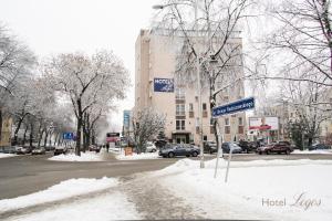 a snow covered street with a building and a street sign at Hotel Logos in Lublin
