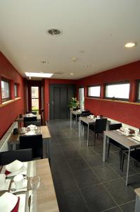 un restaurant avec des tables, des chaises et des murs rouges dans l'établissement Hôtel Le Saint Loup, à Gembloux