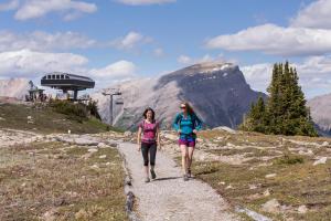 two women walking down a path in the mountains at Sunshine Mountain Lodge in Banff