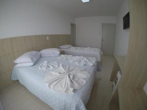 um quarto com 2 camas com lençóis brancos e almofadas em Hotel Dove em Foz do Iguaçu