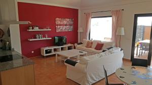 una sala de estar con muebles blancos y una pared roja. en VILLA BERMEJA 10 by Villitas, en Playa Blanca
