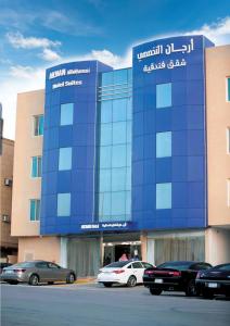 un edificio blu con macchine parcheggiate di fronte di Arjaan Altakhassusi Hotel Suites a Riyad