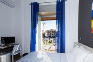 a bedroom with a bed with blue curtains and a window at B&B Albergo Sicilia in Avola