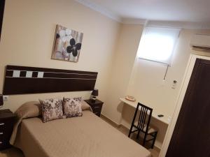 sypialnia z łóżkiem, biurkiem i oknem w obiekcie Hostal Málaga w mieście Arcos de la Frontera