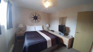 Habitación de hotel con cama y TV en Shoreline Resort Condominiums, en Penticton