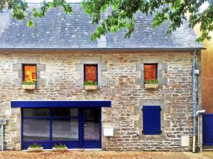 uma casa de pedra com portas e janelas azuis em Brittany Vacation Rental em Plomelin