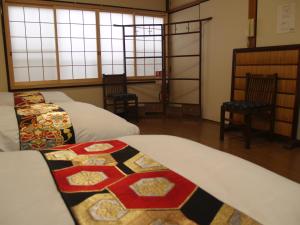een slaapkamer met 2 bedden, 2 stoelen en ramen bij Kyomaru in Kyoto