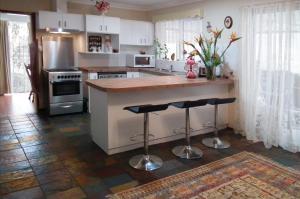 a kitchen with a counter and two bar stools at The Spanish Guesthouse, pets considered in Perth