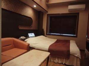 a room with a bed and a chair and a window at Hotel Hyper Noah (Adult Only) in Sakai