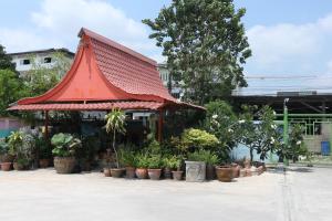a building with a red roof and a bunch of plants at Pa Chalermchai Guesthouse in Bangkok