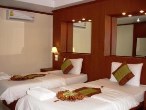 two beds in a hotel room with white sheets at Chinathip Yusabuy in Nan