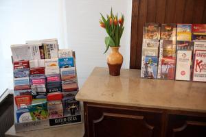 a table topped with books and a vase with flowers at Hotel Lafayette in Hamburg
