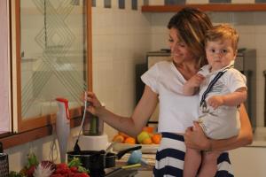 a woman holding a baby in a kitchen at Hotel Tritone Rimini in Rimini