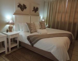 una camera da letto con un grande letto bianco e un tavolo di La Mer Guesthouse a Port Elizabeth