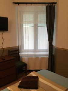 1 dormitorio con ventana, 1 cama y 1 silla en Elvis Guesthouse, en Budapest