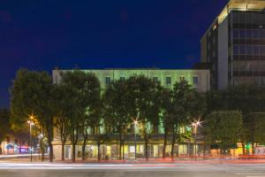 a building with trees in front of it at night at Hotel Igea in Brescia