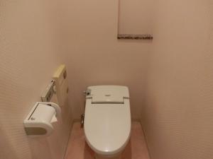 a bathroom with a toilet and a toilet paper dispenser at Hotel Hyper Noah (Adult Only) in Sakai
