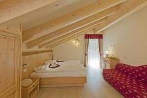 a bedroom with a bed and a red couch at Cesa Melester in Campitello di Fassa