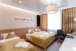 a hotel room with two beds and a chair at Mildom Premium Hotel in Almaty