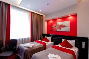 a hotel room with two beds and a red wall at Mildom Premium Hotel in Almaty