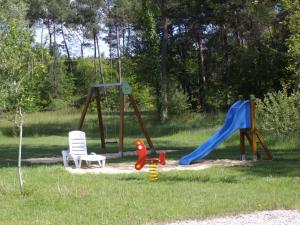 a playground with two swings and a slide at Hôtel Le Grand Chêne in Gièvres