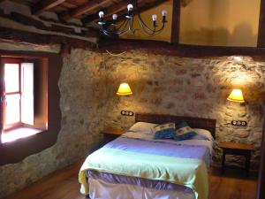 a bedroom with a bed in a stone wall at Hotel y AR Palacio Flórez Estrada in Pola de Somiedo