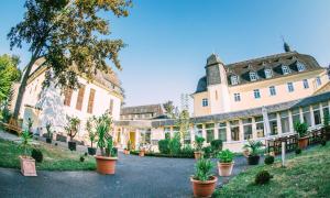 a large building with potted plants in a courtyard at Schlosshotel Domäne Walberberg in Bornheim