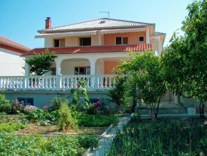 a house with a balcony and a garden at Guest House Mireja in Rab