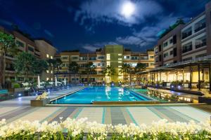 a large swimming pool in front of buildings at night at Jasmine Resort Hotel and Serviced Apartment in Si Racha