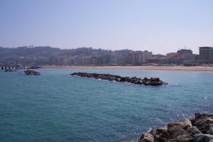 a beach with rocks in the water and buildings at Da Lorella in Gabicce Mare