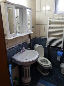 a bathroom with a sink and a toilet and a mirror at Cima Apartment in Pristina